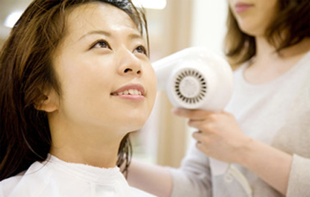 ドライヤーで髪を乾かす女性